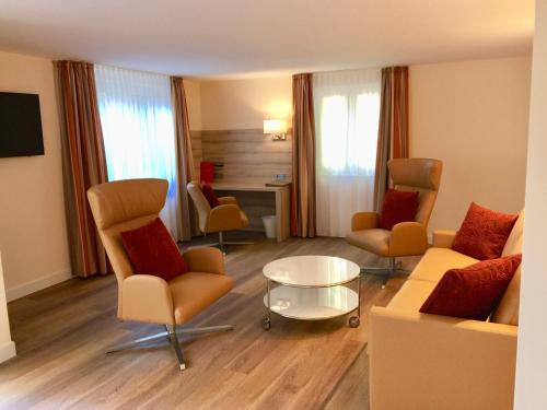 a living room with chairs and a couch and a table at Hotel Wegner - T h e culinary art hotel in Hannover
