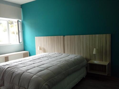 1 dormitorio con cama y pared azul en Vuela Gaviota en Balneario Mar Azul