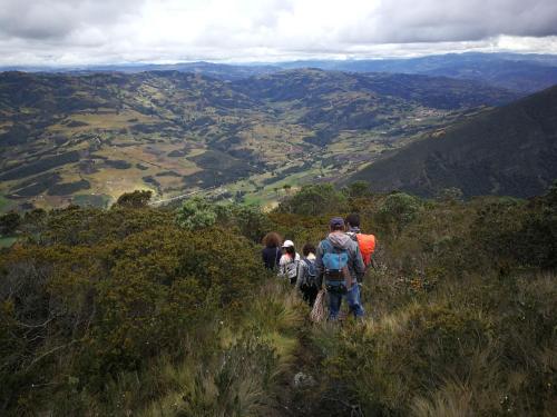 a group of people walking on a mountain trail at Monzaque- paraíso de bachué in El Barrial