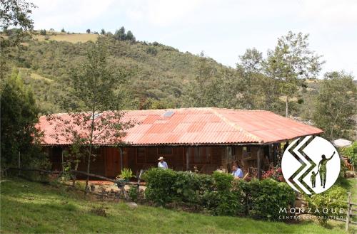 a house with a rusty roof and people standing in front of it at Monzaque- paraíso de bachué in El Barrial
