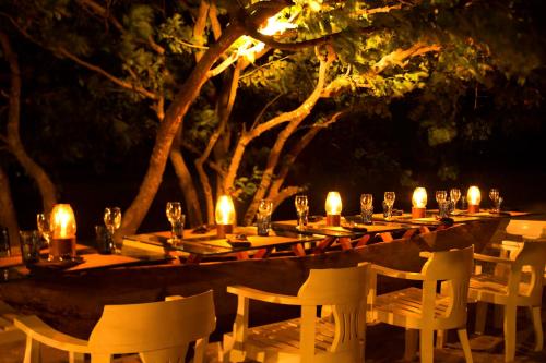 a long table with candles and chairs at night at Maalu Maalu Resort & Spa - Thema Collection in Pasikuda