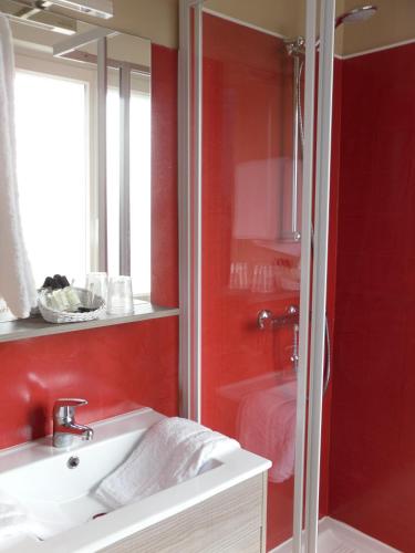 La salle de bains est pourvue d'un lavabo blanc et d'un mur rouge. dans l'établissement The Originals Access, Hôtel Corinna, Royan, à Royan