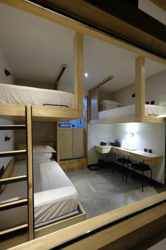 大理市にあるDaLi LOFT Travelling With Hostelの二段ベッド3台とデスクが備わる客室です。