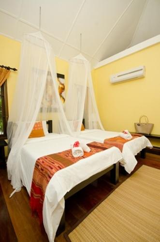a bedroom with two beds with mosquito nets at Villa Khao Phaengma in Wang Nam Khieo