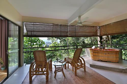 a room with a tub and some chairs and a table at Ambong Rainforest Retreat in Pantai Cenang