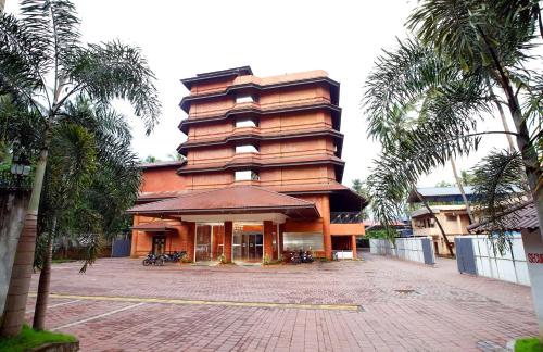 a large building with palm trees in front of it at Hotel Park Residency in Nilambūr