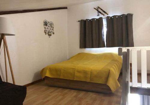 レ・ザングルにあるAppartement Cosyのベッドルーム1室(黄色い毛布付きのベッド1台付)