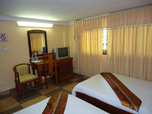 a hotel room with two beds and a desk and a television at U-Dara Inn Guesthouse in Siem Reap