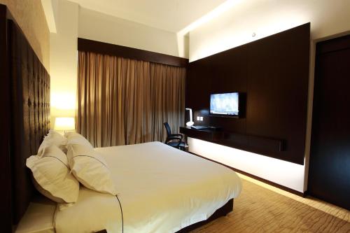 a hotel room with a bed and a television at Symphony Suites Hotel in Ipoh