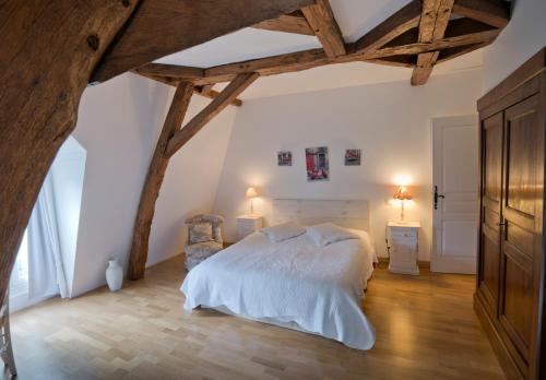 um quarto com uma grande cama branca e pisos em madeira em La Bastide du Roy em Villamblard