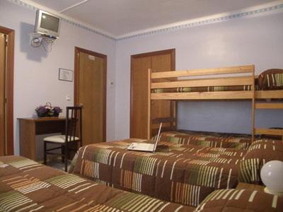1 dormitorio con 2 camas y ordenador portátil en la cama en Hostal Oasis en Fraga