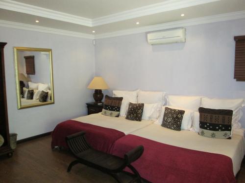 a hotel room with two beds and a mirror at Tuskers Bush Lodge B&B in Hartbeespoort
