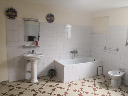 a bathroom with a sink and a tub and a toilet at Joli jardin en ville in Yaoundé