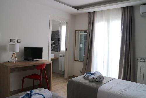 a hotel room with a bed and a desk and a window at Musmelia Rooms in Mussomeli