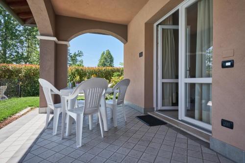 a patio with white chairs and a table on a balcony at Villaggio Turistico Lugana Marina in Sirmione