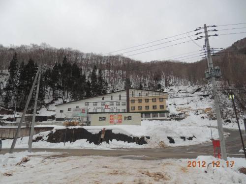a large building in the snow next to a road at Naeba Lodge Oka in Yuzawa