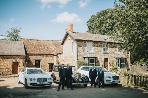 a group of four men in suits standing next to cars at Slapton Manor in Towcester