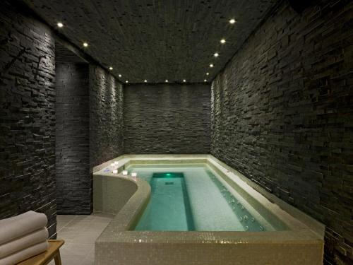 a swimming pool in a room with a brick wall at Le Faucigny - Hotel de Charme & SPA in Chamonix-Mont-Blanc
