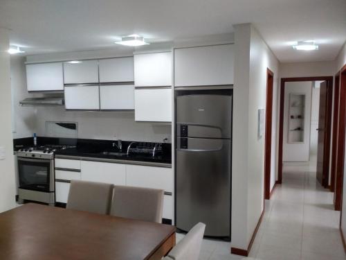 cocina con nevera de acero inoxidable y mesa en Mahalo Happy Apartment, en Florianópolis