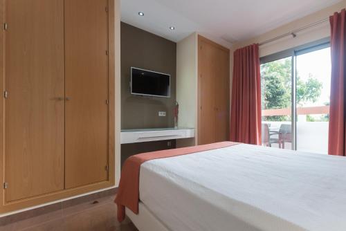 a bedroom with a bed and a tv on a wall at Hotel Pradillo Conil in Conil de la Frontera