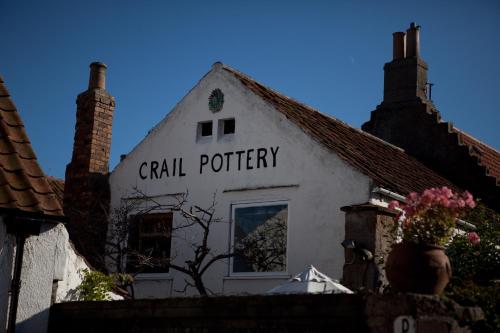 a white building with a sign that readsril pottery at Honeypot Guest House in Crail
