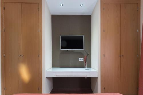 a room with a tv on a wall with a desk at Hotel Pradillo Conil in Conil de la Frontera