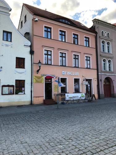 un grand bâtiment rose sur une rue pavée dans l'établissement Kosmos 9 - Apartament Astro, à Toruń