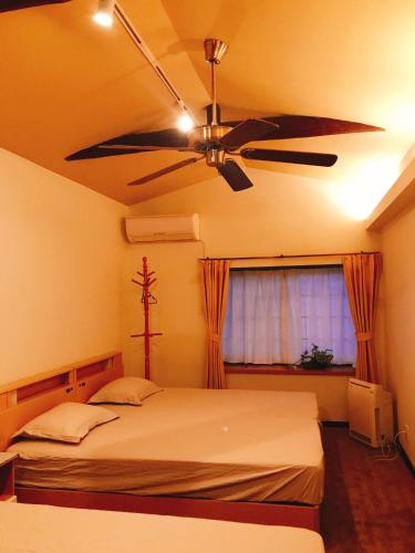 a bedroom with a ceiling fan and a bed at HimawariRyokanひまわり旅館 in Okayama