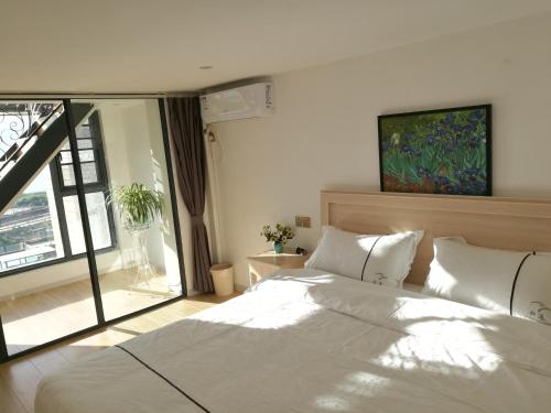 a bedroom with a white bed and a large window at Home Bird Garden Villa in Dali