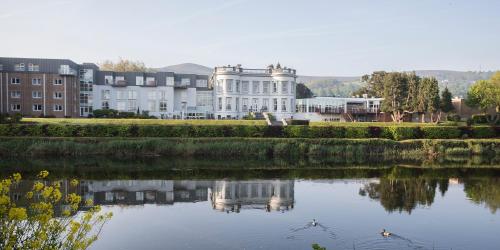 a large white building sitting next to a lake at Hotel Minella & Leisure Centre in Clonmel