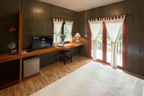 a living room with a desk with a computer and windows at Chiang Dao Reset in Chiang Dao