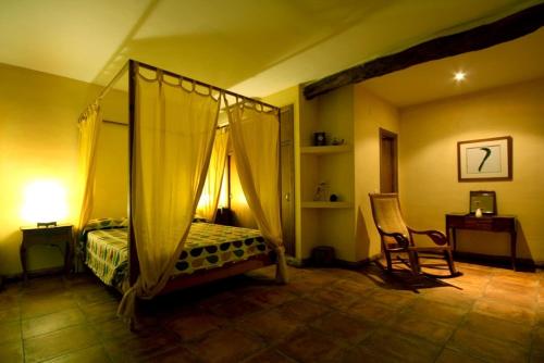 a bedroom with a canopy bed and a chair at Posada Tresmentiras in Aldeanueva del Camino