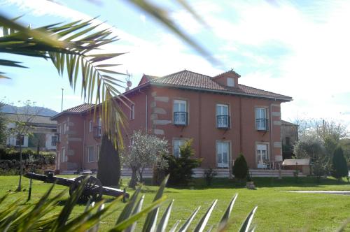 a large red house in a field of grass at Posada Tresmentiras in Aldeanueva del Camino