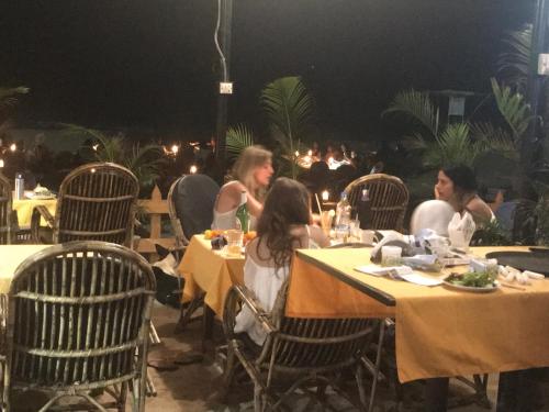 un grupo de personas sentadas en mesas en un restaurante en Roundcube Beach Bungalows Patnem, en Patnem