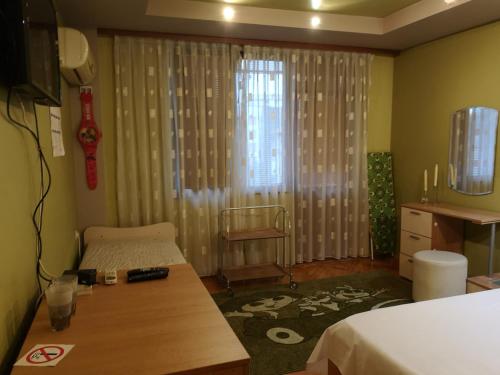 a bedroom with a bed and a table and a window at Стаи за гости "Панега" in Pleven