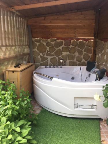 a bath tub sitting in a yard with a stone wall at Eden Lilli B&B in La Pieve