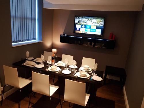 a dining room with a table with chairs and a television at Chatterley House in Nottingham