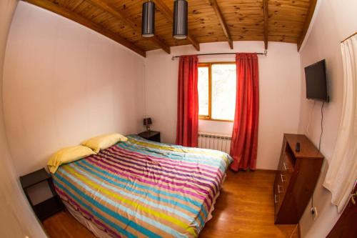 1 dormitorio con 1 cama y una ventana con cortinas rojas en Isla de Lagos II en Ushuaia