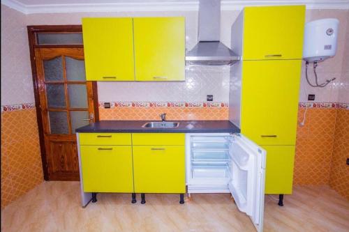 una cocina con armarios amarillos y fregadero en Appart Hotel Excellent, en Nador