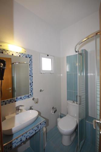 a bathroom with a sink and a toilet and a shower at ZEPHYROS ROOMS in Ormos Panagias