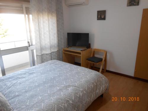 a bedroom with a bed and a desk with a television at Sinos Rio Tinto in Campainha