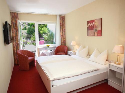 una habitación de hotel con una gran cama blanca y una ventana en Gästehaus Kramer - Emde, en Willingen