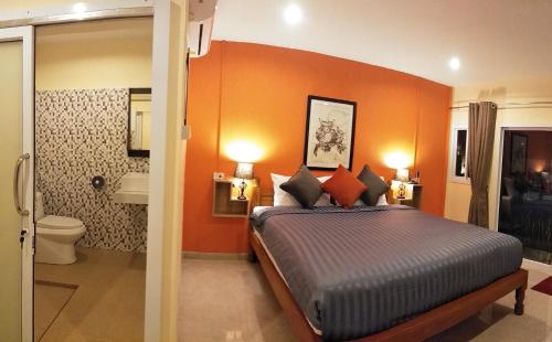 ein Schlafzimmer mit einem Bett mit einer orangefarbenen Wand in der Unterkunft BeauBo Beach in Baan Tai