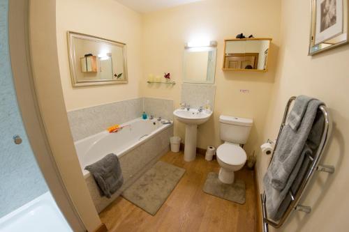 a bathroom with a tub and a toilet and a sink at Grey Stag Apartment in Nairn