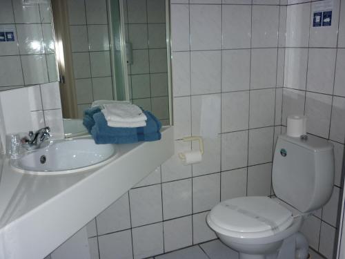 a bathroom with a toilet and a sink and a mirror at Logis Hotel Du Midi in La Roche-en-Ardenne