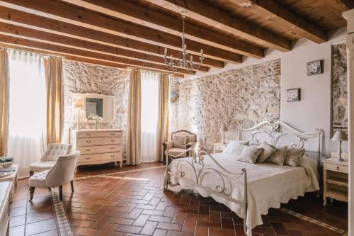 サン・ピエトロ・イン・カリアーノにあるB&B - Relais de charme la Caminellaの白いベッドと石の壁が備わるベッドルーム1室