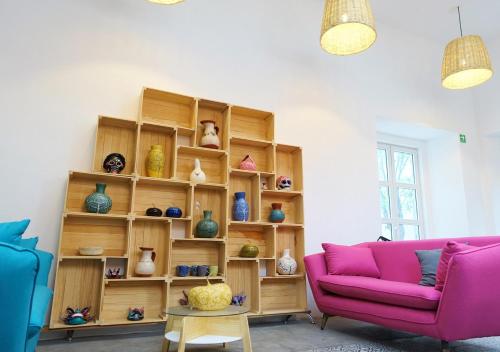 a living room with a pink couch and shelves of vases at Hotel Mamá Carlota in Querétaro
