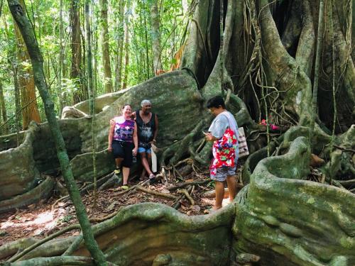 three people standing in front of a tree with roots at Baan Sangchan in Ko Kood