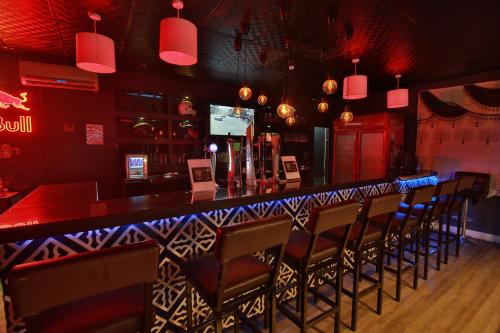 a bar in a restaurant with red walls and chairs at Mutrah Hotel in Muscat