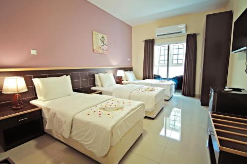 a hotel room with two beds and a television at Mutrah Hotel in Muscat